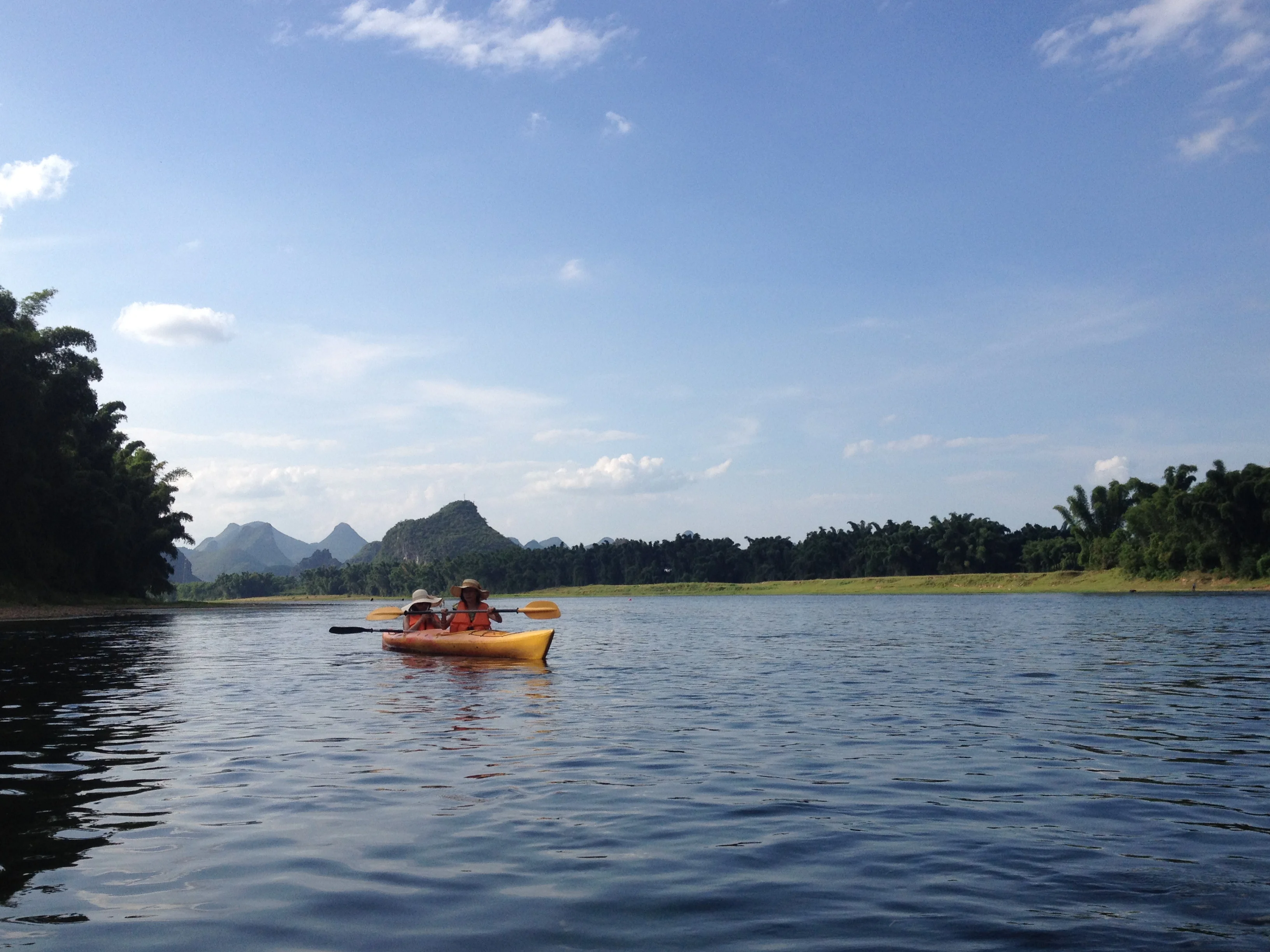 Group of participants paddling the Yulong River with karst peaks rising in the background, Yangshuo