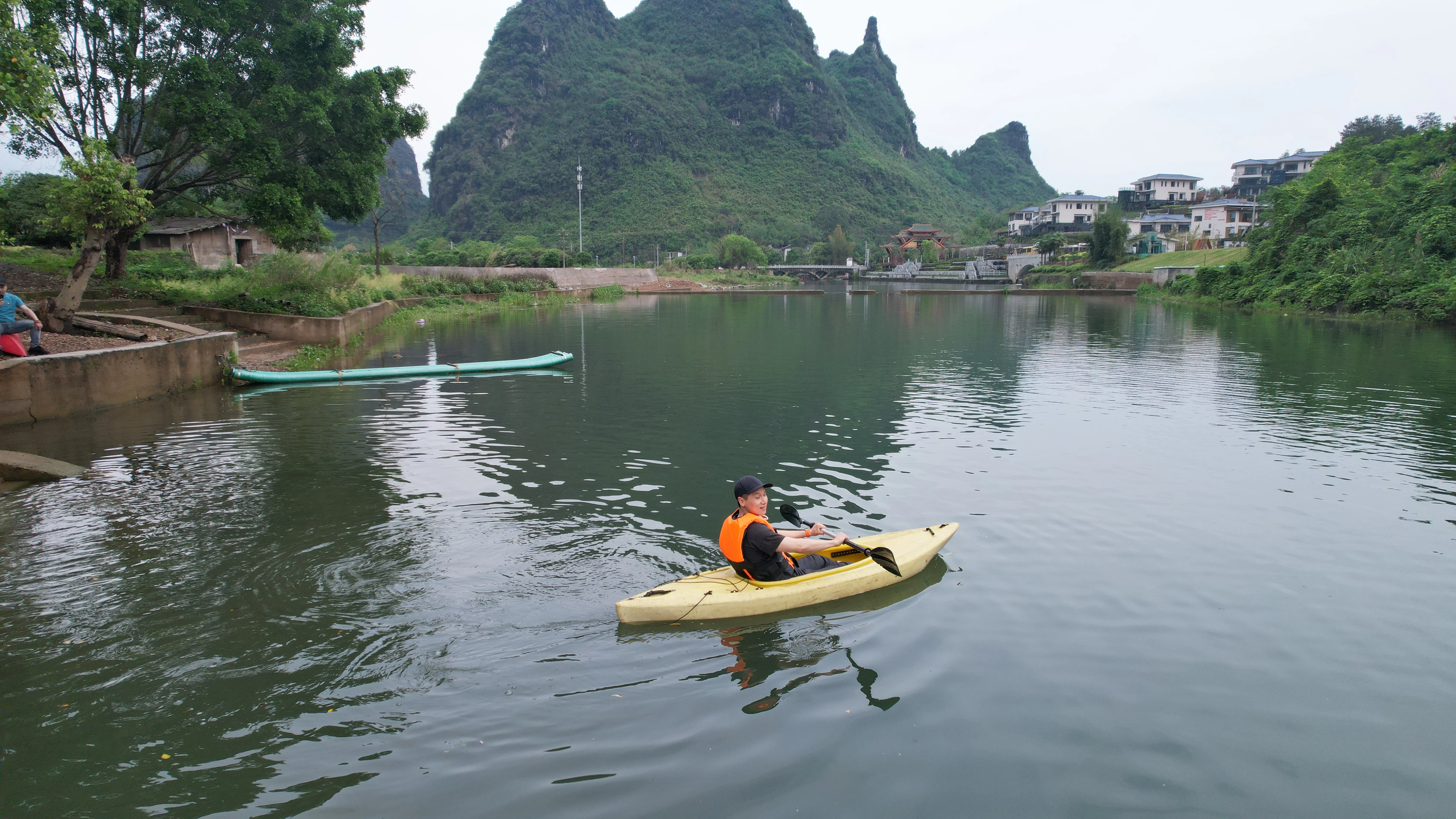 Group in life jackets on the calm Yulong River with lush karst mountains reflected in the water, Yangshuo