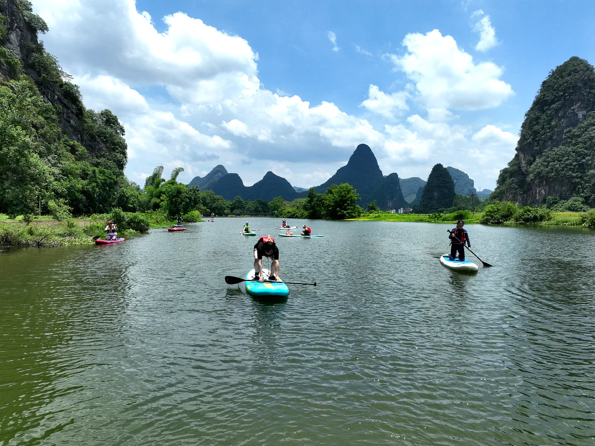 Aerial view of participants in life jackets on paddleboards on the Yulong River through the Yangshuo karst