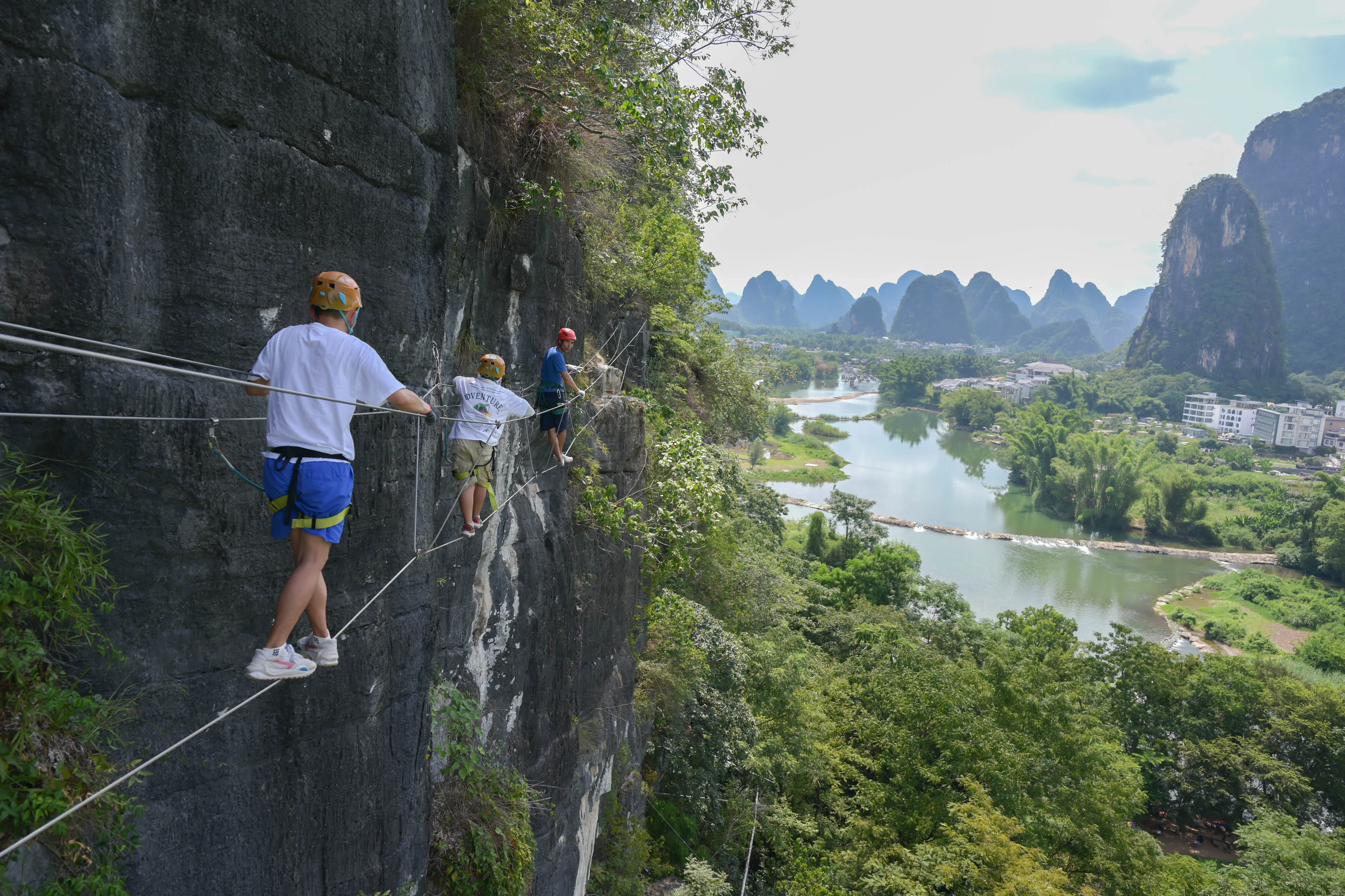 Guide briefing participants on via ferrata technique at the cliff entrance in Yangshuo