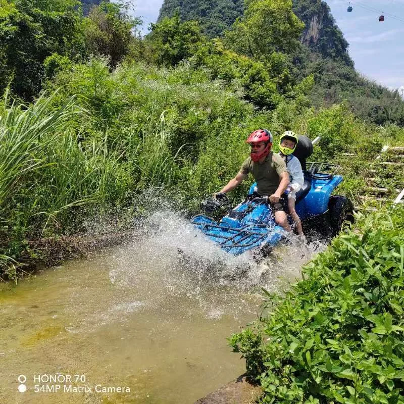 Rock climber in helmet ascending a natural limestone karst wall with green vegetation, Yangshuo China