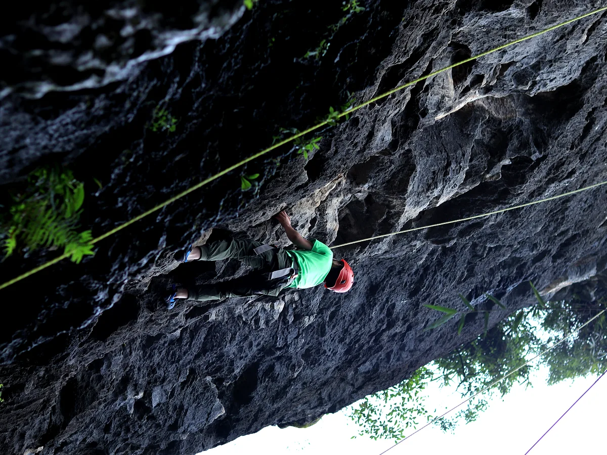 Climber in safety harness on an outdoor karst rock face with rope protection, Yangshuo China
