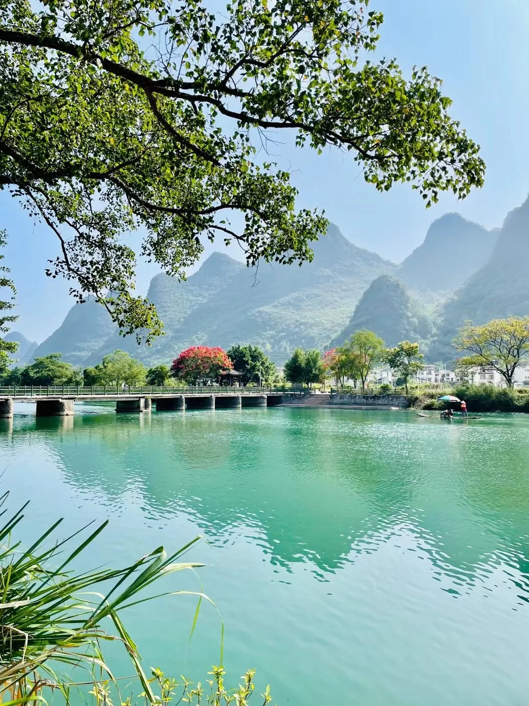 Group of participants gathered at a mountain viewpoint with a vivid rainbow arching over the green valley, Guangxi China